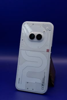 Close-up of a modern white smartphone with dual cameras against a blue background.