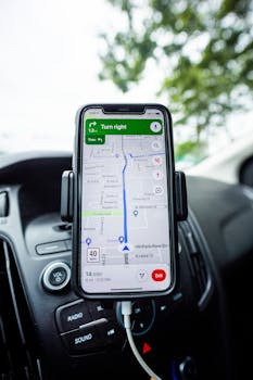 Close-up of a smartphone with GPS navigation app mounted on car dashboard.