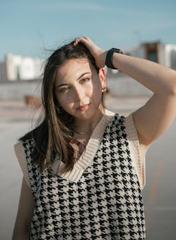 Portrait of a young woman in a stylish houndstooth sweater, enjoying a sunny day outdoors.